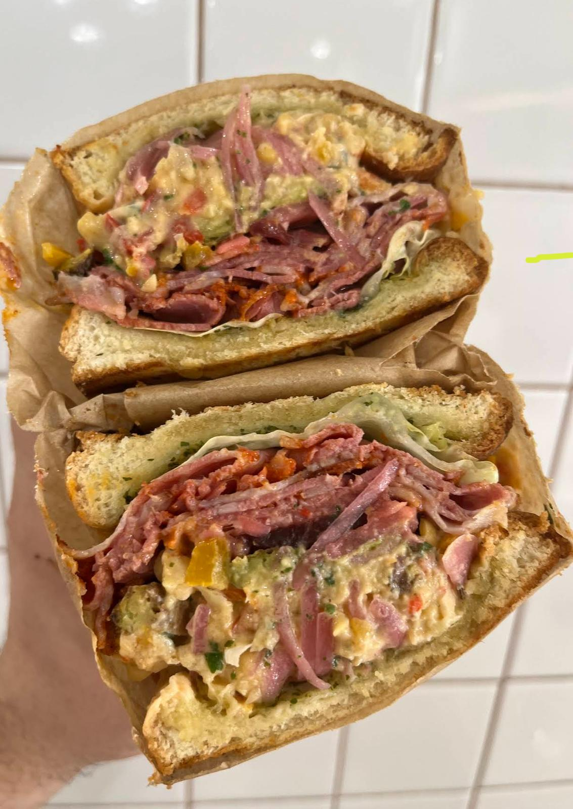 Sandwich pastrami coupé en deux, généreusement garni